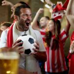 A man cheering in a crowded pub with a football in hand, bringing to life some of the most interesting World Cup facts