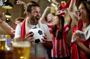 A man cheering in a crowded pub with a football in hand, bringing to life some of the most interesting World Cup facts