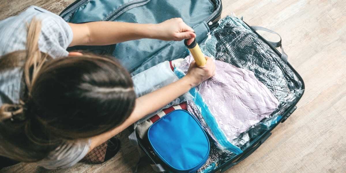 aerial shot of a woman using vacuum compression bags to pack light, one of the key steps on our international travel checklist