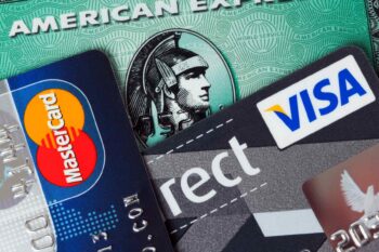 three credit cards in a pile including an American Express card which comes with American Express travel insurance