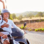 Mature Couple Riding Motorcycle Along Country Road