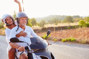 Mature Couple Riding Motorcycle Along Country Road