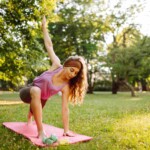 A woman practices yoga in a sunlit park as part of a plan to stay healthy while traveling