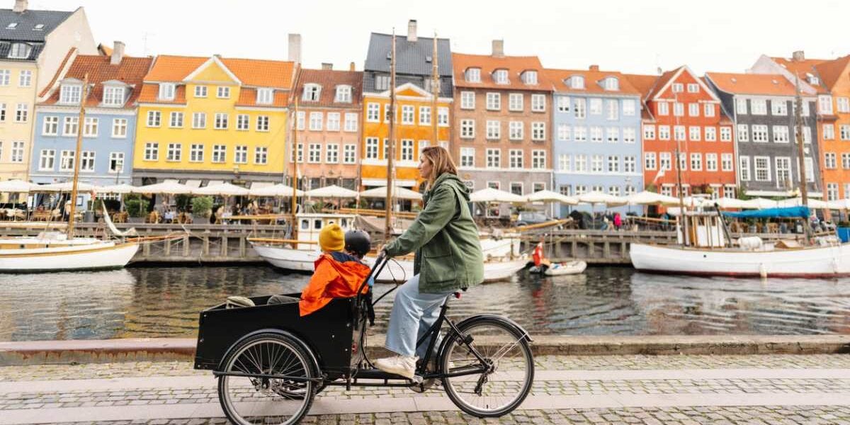 a mother cycling her cargo bike with her children in Copenhagen, one of the best places to raise a family in 2025