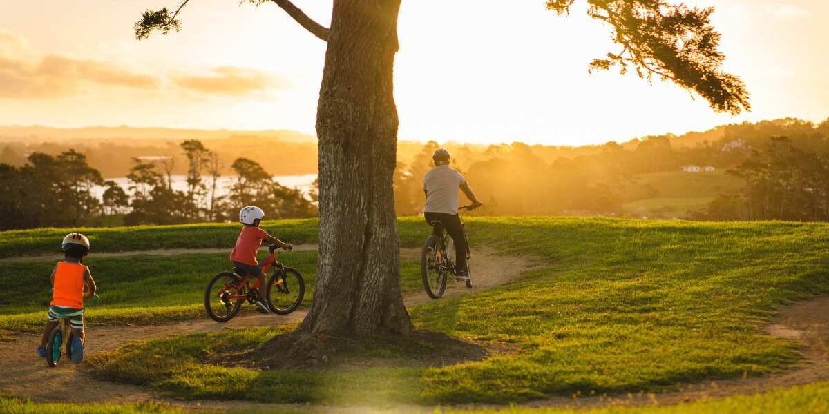 a family cycling over fields against a sunset in New Zealand