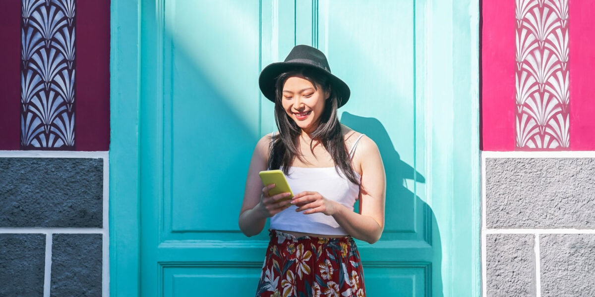 a happy girl using an app to manage her money, one of our top study abroad tips for students