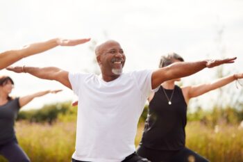 a smiling man enjoying an outdoor yoga class in one of the healthiest countries in the world