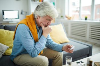 An elderly man reading reading the label on his medication wondering if he can travel internationally with prescription medication 
