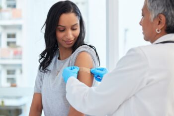 a woman getting a shot to make sure she meets the vaccination requirements for traveling abroad