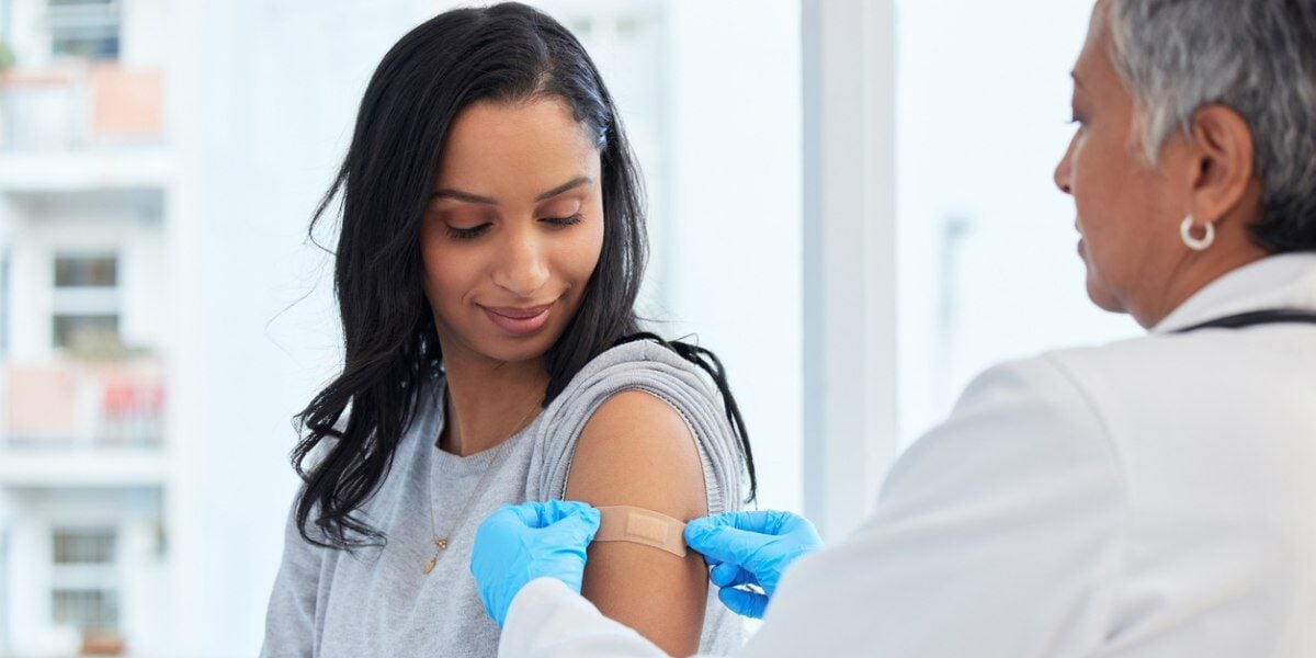 a woman getting a shot to make sure she meets the vaccination requirements for traveling abroad