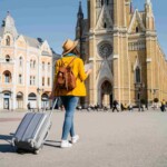 a woman pulling a suitcase along a square in Spain, having researched does my health insurance cover international travel