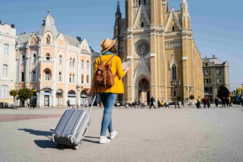 a woman pulling a suitcase along a square in Spain, having researched does my health insurance cover international travel