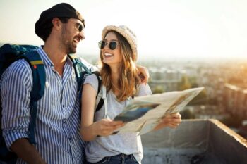 A young couple with backpacks smiling while holding a map, symbolizing the peace of mind and freedom that comes with single-trip travel insurance coverage