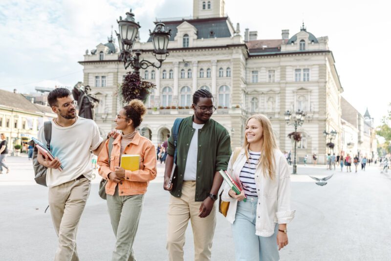A group of happy students walking down a street, having secured international student insurance, also known as health insurance for students studying abroad