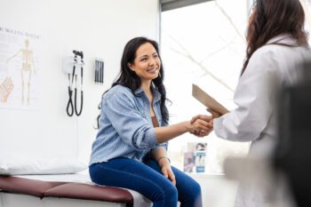 Mid adult female patient shakes hands with her doctor while learning about ACA compliant plans