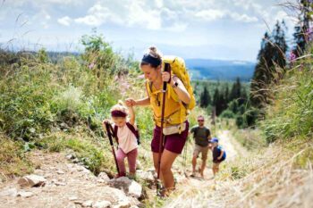 A husband and wife hiking with two young children happily talk about their decision to buy international health insurance.