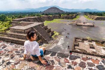 a female tourist overlooking ancient pyramids in Mexico, having bought travel insurance for Mexico before her trip