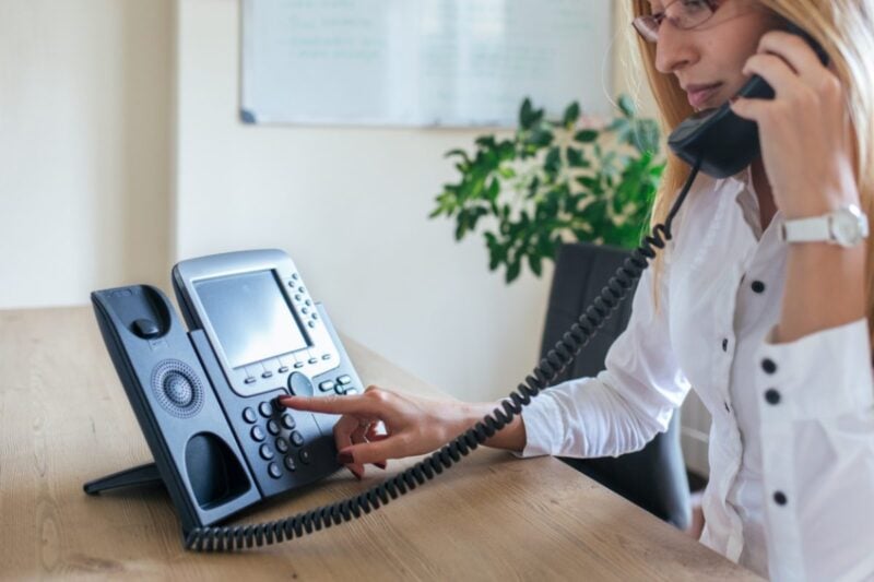 a business woman making a call on a landline phone using our international calling codes list