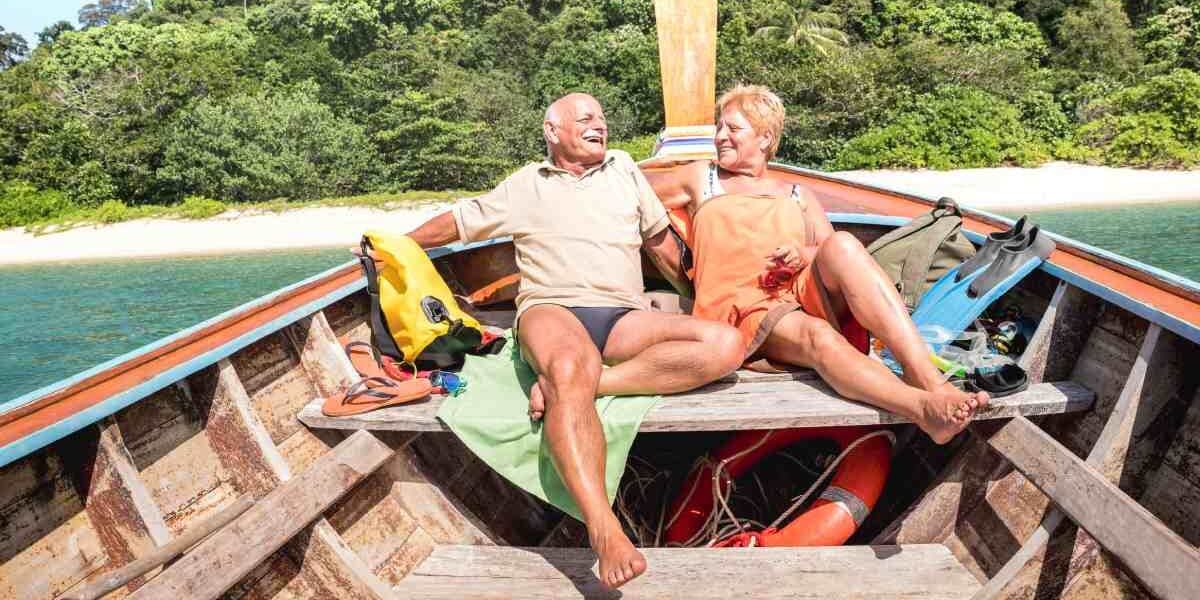 a happy senior couple enjoying an island hopping tour in a boat in Thailand, where travel insurance for Thailand is highly advisable 