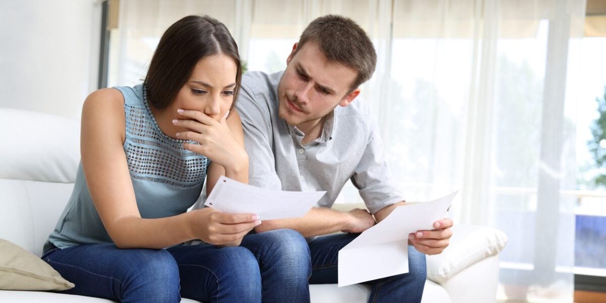 a couple looking shocked at a costly medical bill, one of the harsh realities of the US healthcare system