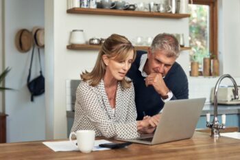 a couple on a laptop in a kitchen, researching how coverage options impact insurance premiums