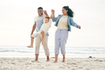 a family smiling and holding hands on a beach, knowing they are protected by health insurance from one of the best global health insurance provides in 2025