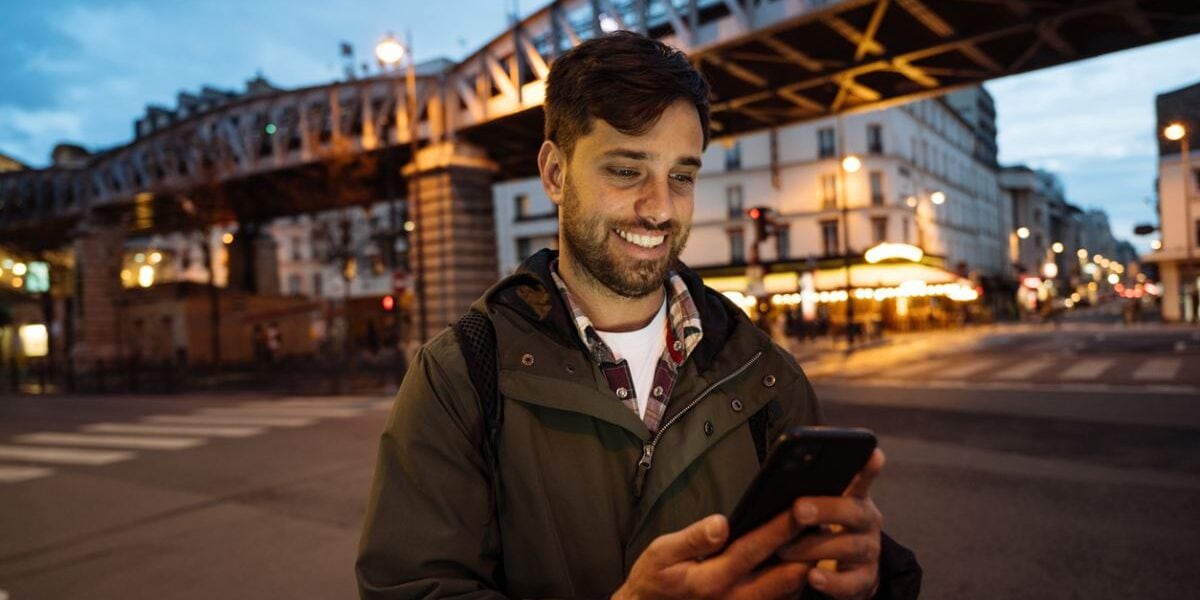 Young man using smart phone to book an Uber in France