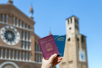 the hand of a person holding Italian and Brazilian passports, indicating some of the easiest countries to get dual citizenship