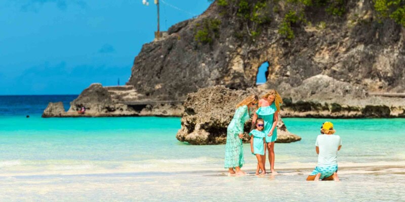a family relaxing on a beach in the Philippines, one of the best countries to move to from the USA with family
