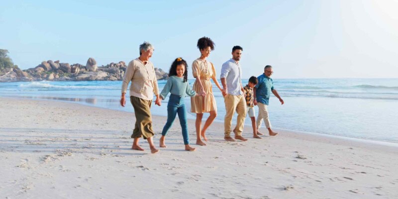a large family walking on a beach, showing how multigenerational travel is a major travel trend in 2025