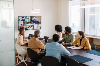 a team engaging with remote colleagues via a large screen, illustrating the advantage of partnering with an international PEO to hire and manage global talent seamlessly