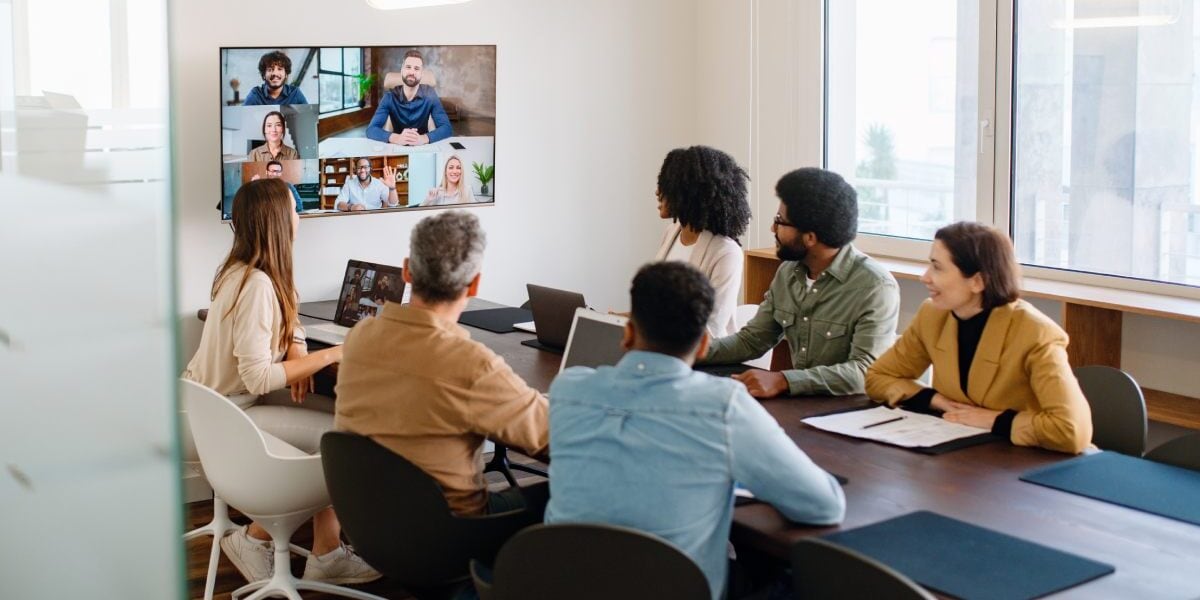 a team engaging with remote colleagues via a large screen, raising the question of whether group vs individual insurance is best for global health coverage