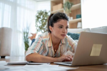 a young woman researching how to choose travel medical insurance on her laptop at home