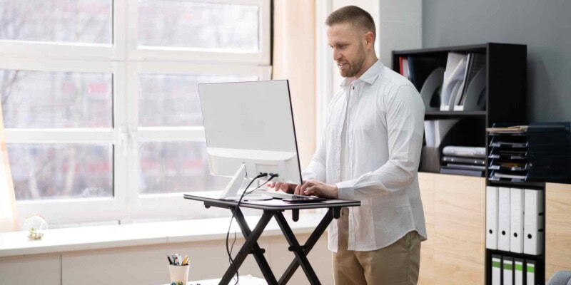 a man working at a stand-up desk in his home office, one of the key strategies for how to manage a remote team successfully