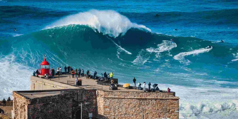 tourists watching a huge wave in Nazare, Portugal