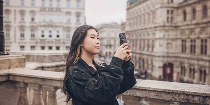 a solo female traveler taking a photo on her phone in the center of Vienna, Austria, one of the safest destinations for solo travel for women
