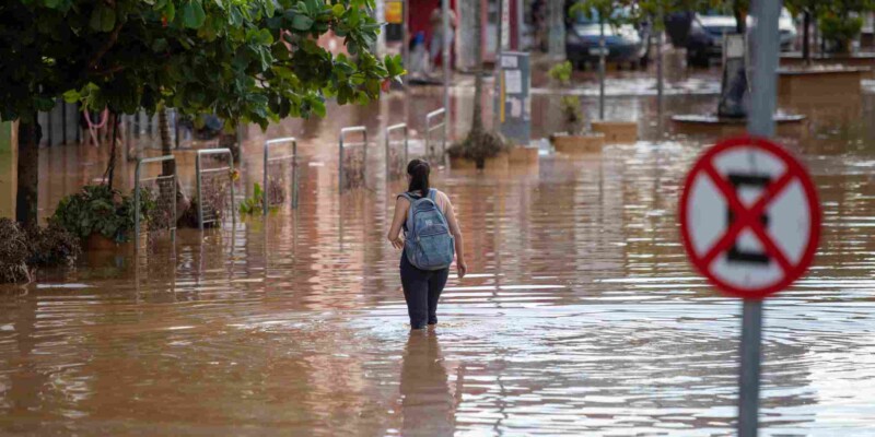 a woman wading through a flooded street in Brazil