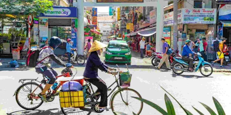 a local woman cycling on a bike in a busy street in Vietnam, one of the cheapest countries to live in