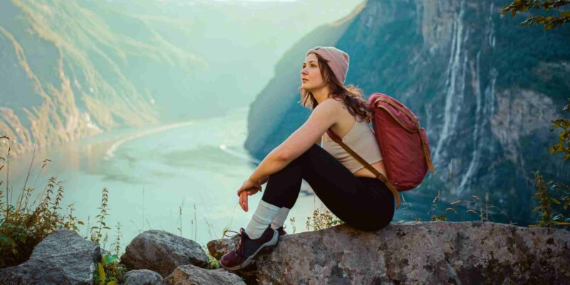 a woman sitting near Seven sisters waterfall in mountains in Norway, one of the best countries for solo travel for women