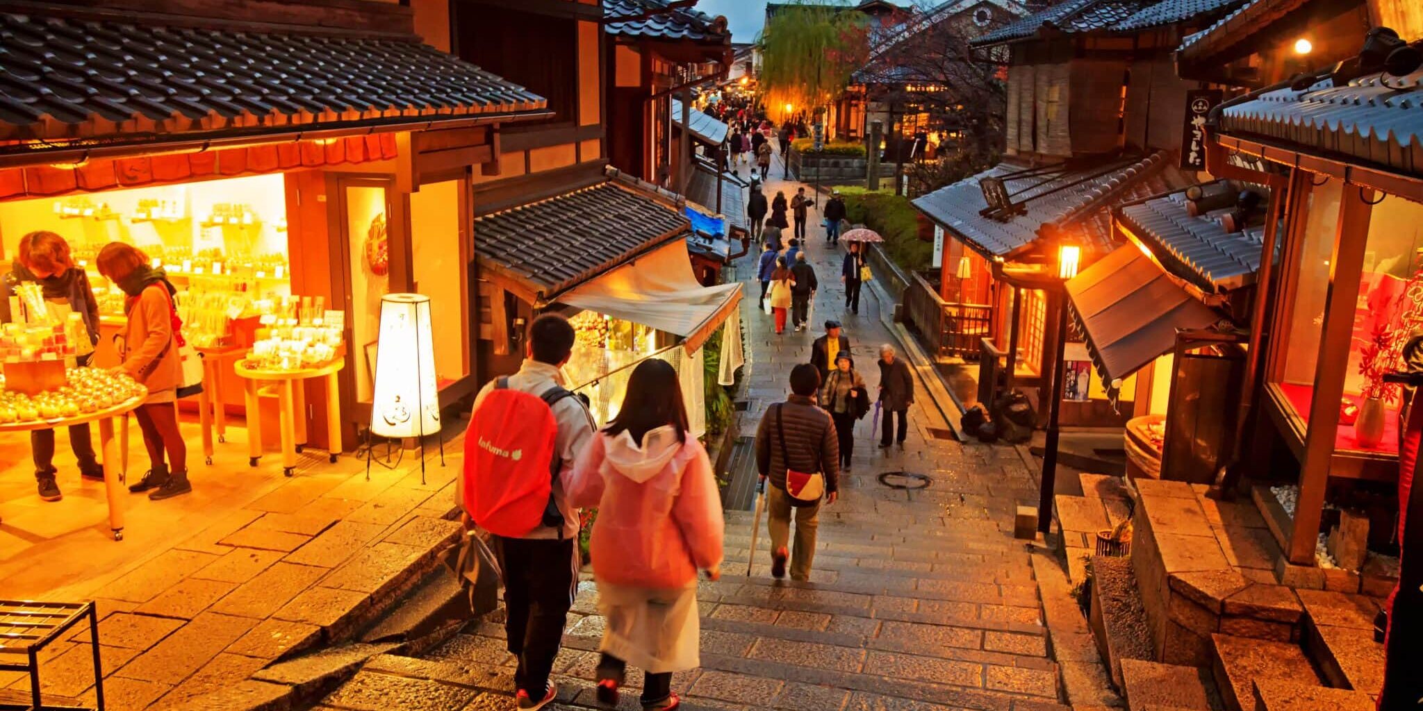 two tourists walking down a slope in Kyoto at night, indicating the importance of securing travel insurance for Japan