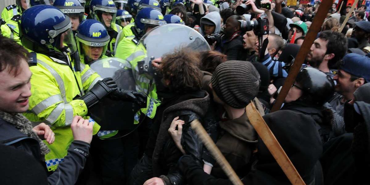 Protesters and police clash at an austerity rally in London, indicating the need to buy UK travel insurance for travel disruptions