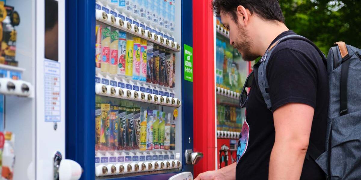 a tourist buying a beverage at a Japanese vending machine