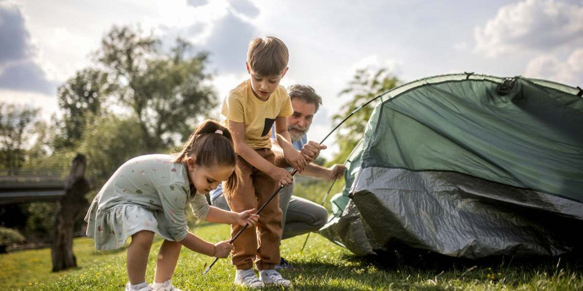 a family pitching a tent on a camping trip, one of the best family vacation ideas for 2025
