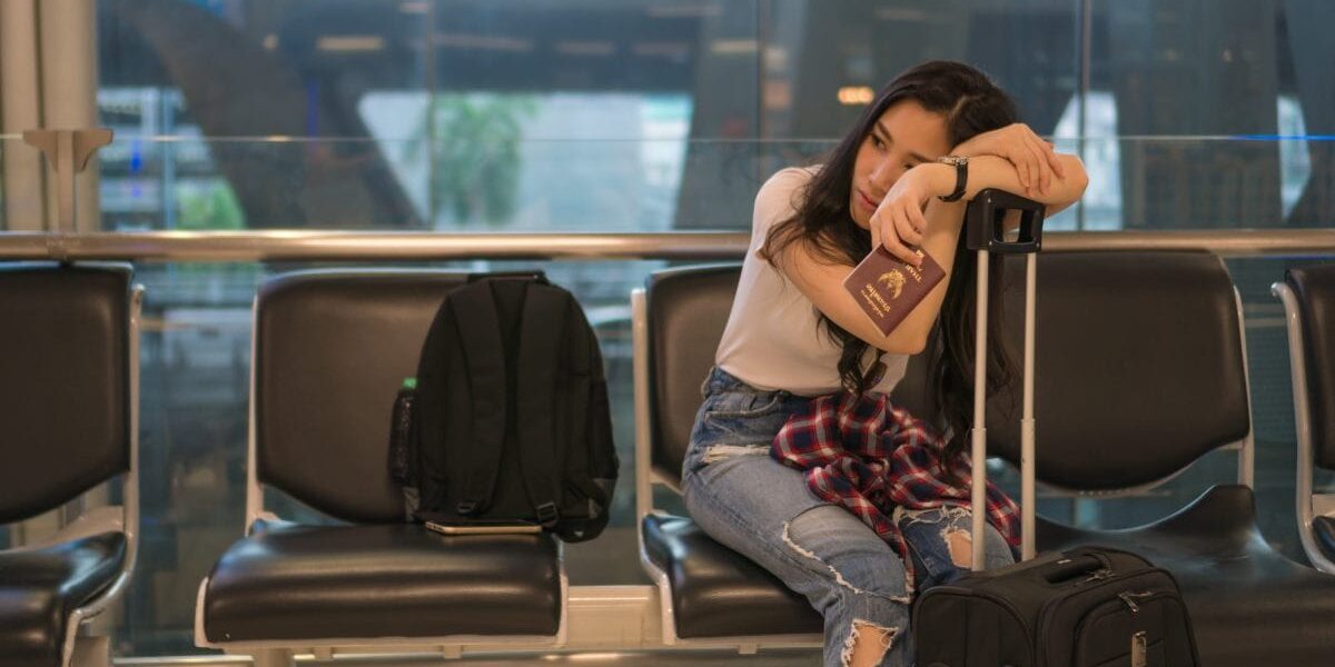 a young girl waiting at an airport gate for her delayed flight, glad that she chose to purchase trip cancellation travel insurance