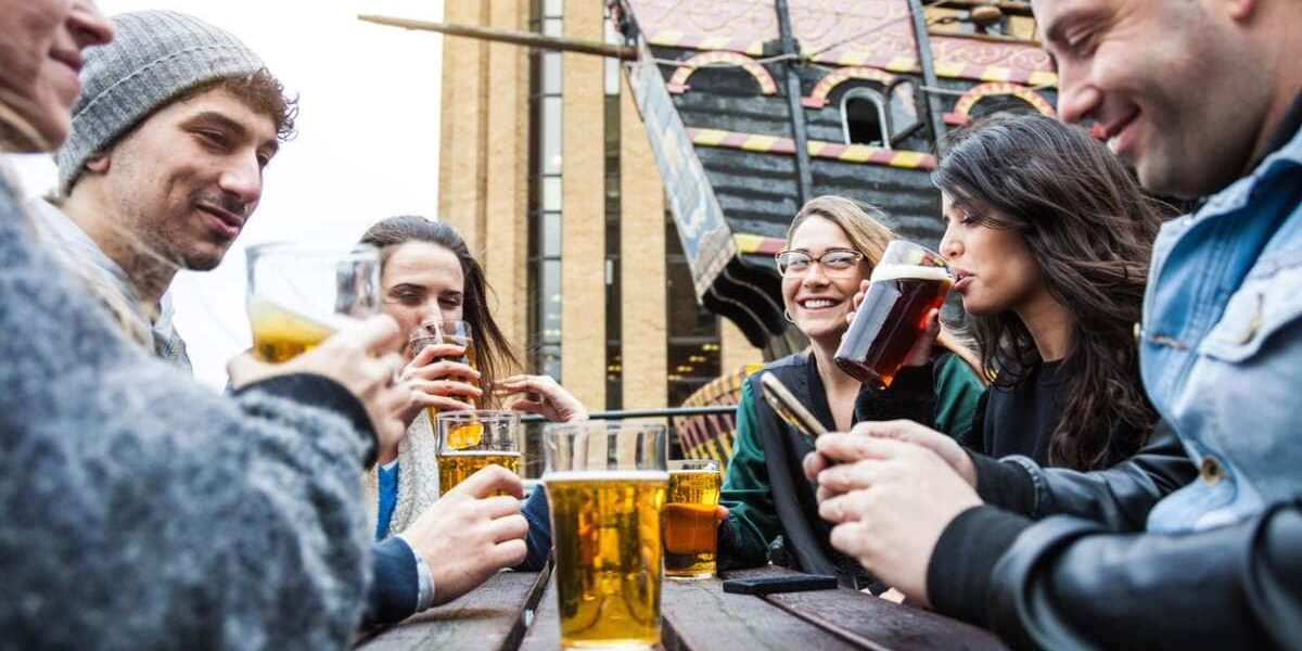 friends drinking beer outside a London pub, where tourists are advised to purchase UK travel insurance