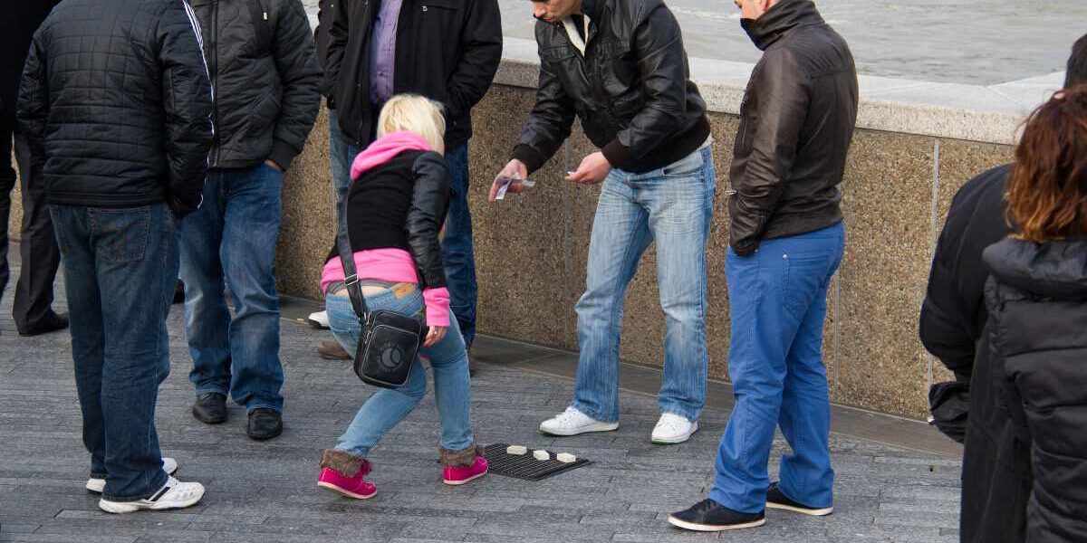 a female tourist falling victim to one of the shell game travel scams in London, UK