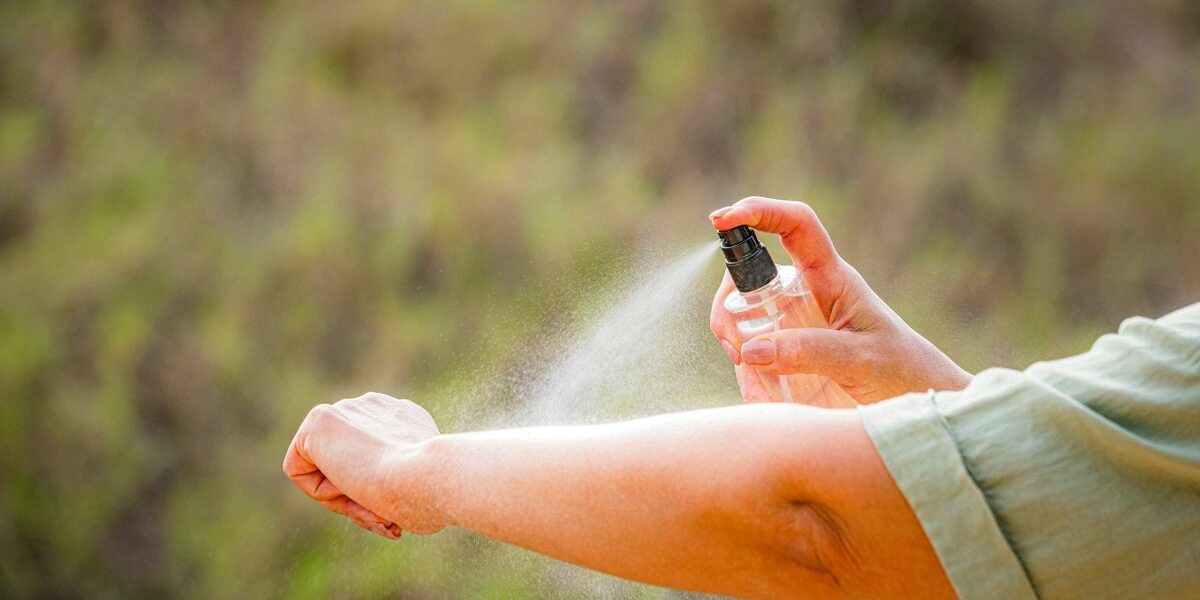 a traveler applying insect repellent to prevent malaria transmission while traveling abroad