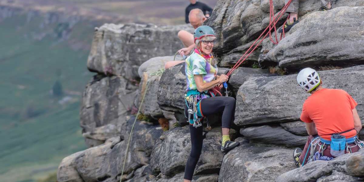 a woman rock climbing with a group in the UK, having bought UK travel insurance for extreme sports