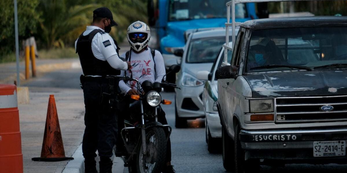a policeman checking a motorcyclist's paperwork on the side of a busy road in Mexico