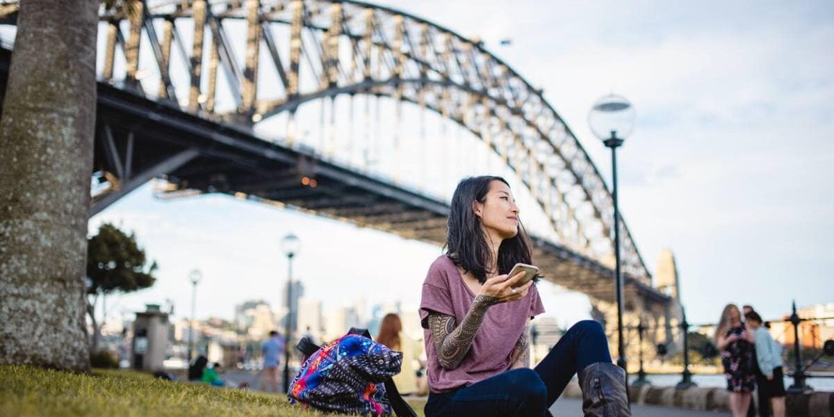 A woman relaxing by Sydney Harbour Bridge in Australia, one of the best countries to live in as an expat